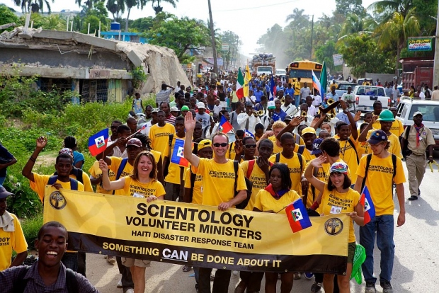 Szcientológia önkéntes lelkészek Haitiről és más országból felvonulást tartanak Port-au-Prince egyik külvárosi negyedéből, Carrefourból kiindulva Léogane városáig a Lobogó Napja ünnepének alkalmából, ami a francia elnyomás és rabszolgaság alóli 1803-as felszabadulás ünnepe.